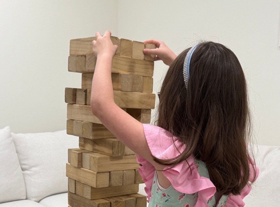 A young client playing giant Jenga in a therapy room at Caladrius Therapy